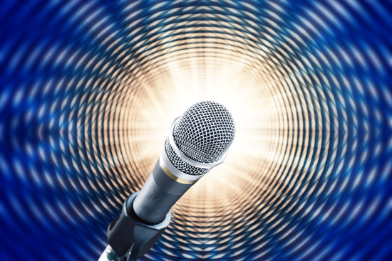Close up of microphone on blue background simulating sound waves
