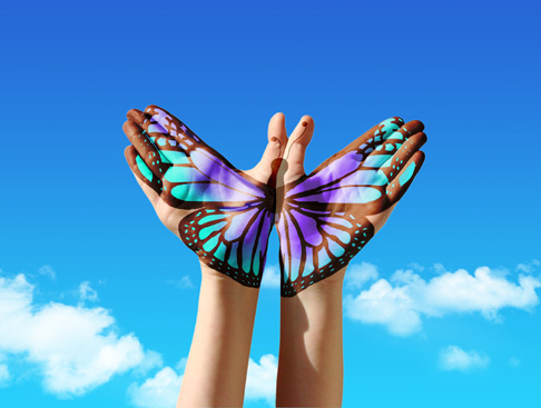 Painting of a butterfly across two hands against blue sky